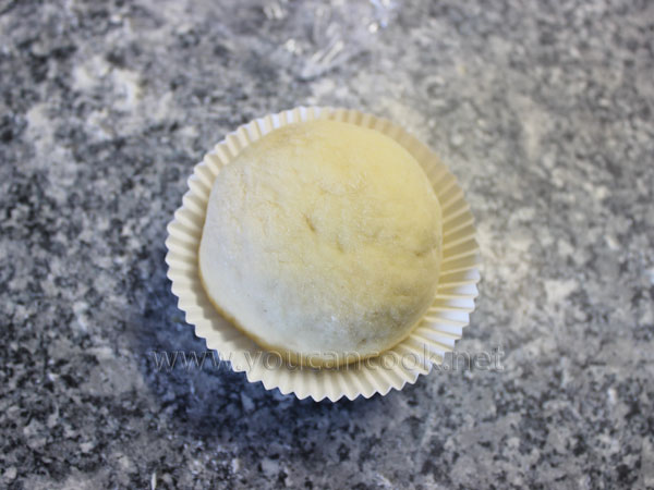 Den mit der Füllung geformten Teig in das Muffins-Papierförmchen geben